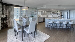 Une cuisine moderne dotée d’un îlot central, de tabourets de bar et d’un coin repas avec une table et des chaises.
