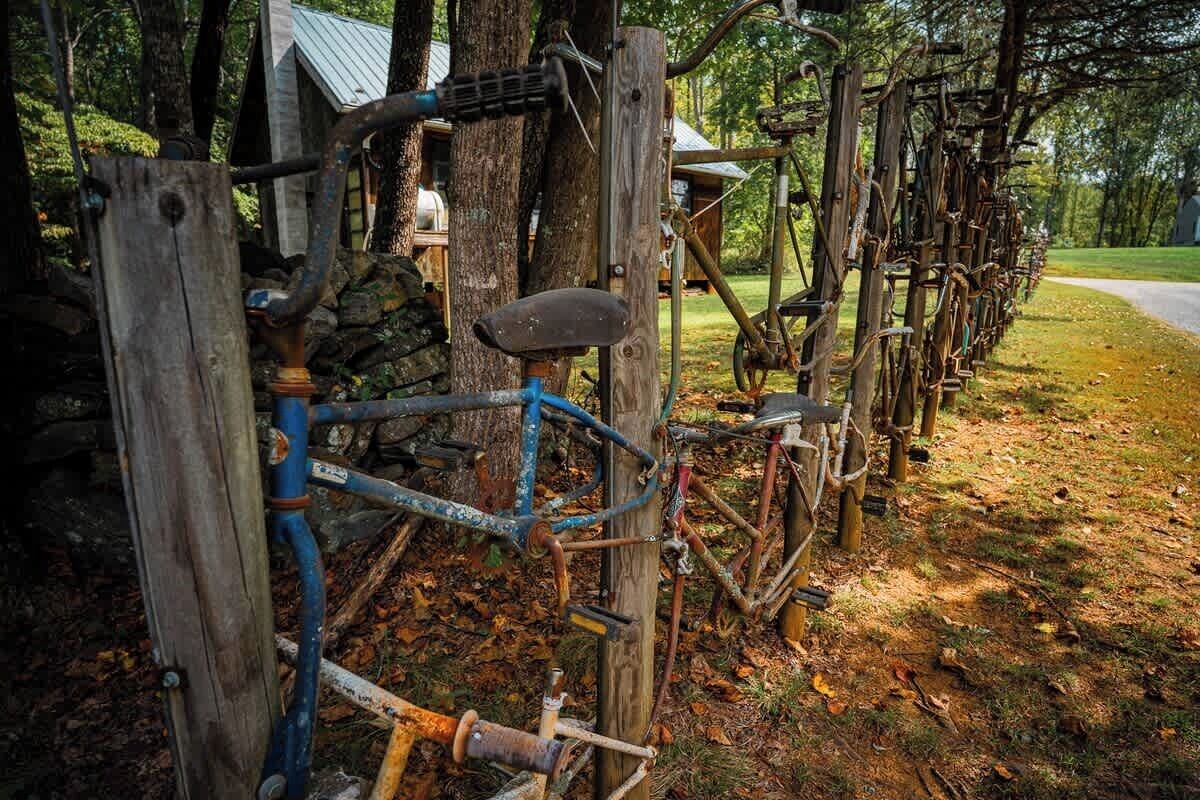 A rustic outdoor setting with a wooden fence, a stone wall, and a bicycle.