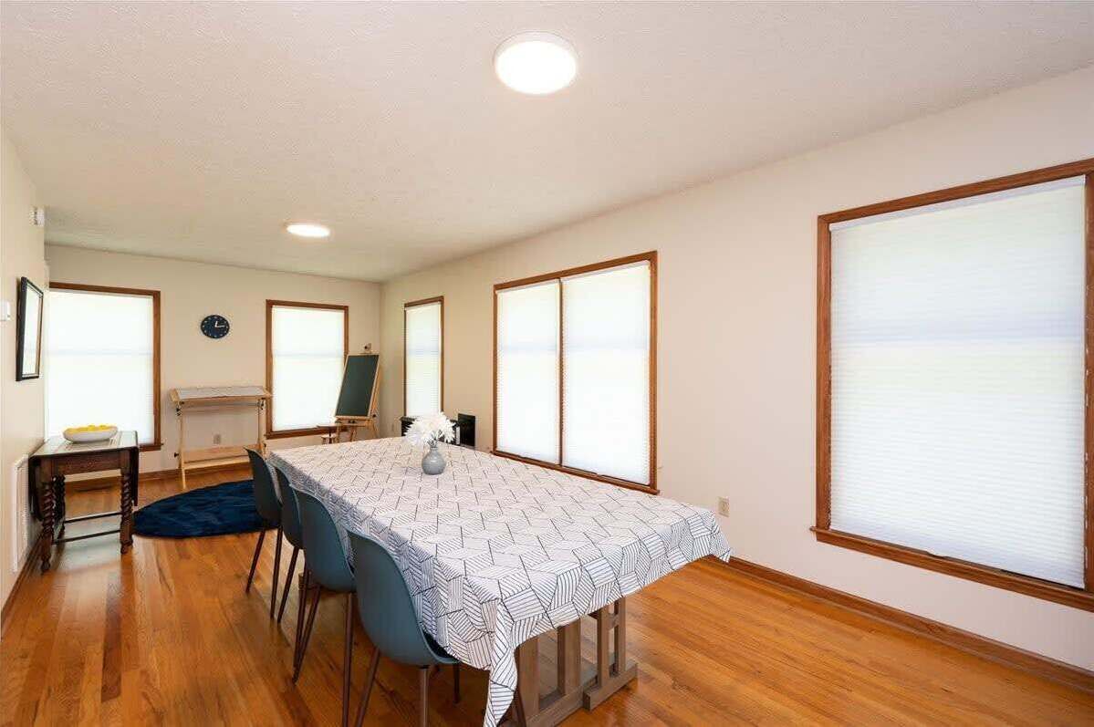 Un espace repas comprenant une table, des chaises, une horloge et de grandes fenêtres.