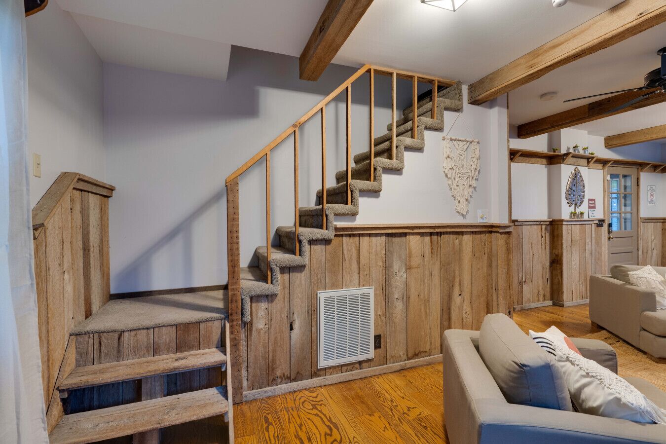 A wooden staircase with a handrail, a white wall, and a wooden floor.