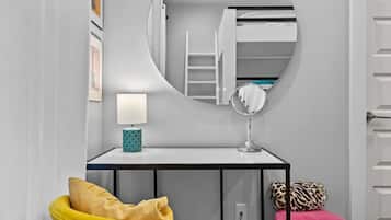 Une petite pièce comprenant un lit superposé, un petit bureau avec un miroir, une lampe et une chaise.