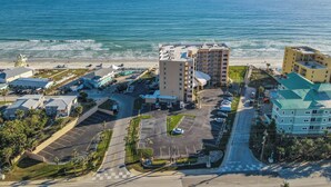 A coastal hotel with multiple buildings, parking areas, and a beach view. - Oceania Beach Club 106 (New Smyrna Beach)