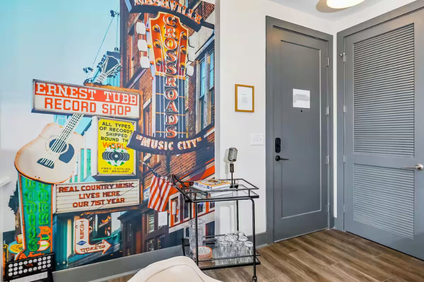 A room with a mural of a vintage music city, a record shop sign, and a door with a closed shutter.