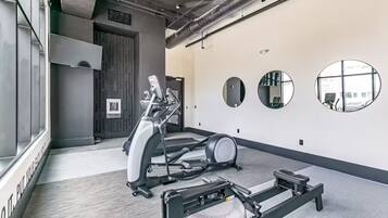 Uma academia com esteiras, elípticos e um banco de musculação.