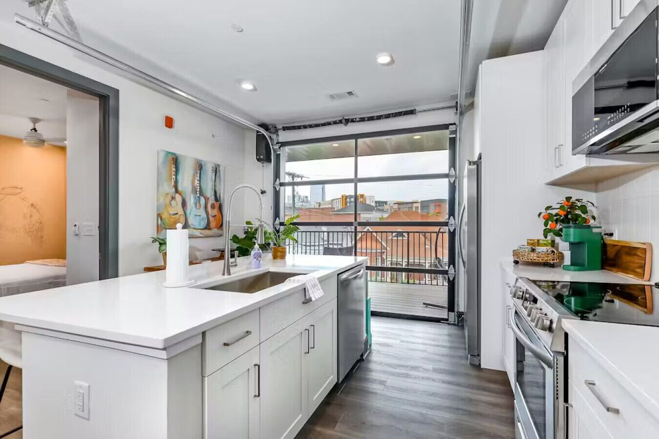 A modern kitchen with a large island, a balcony with a view, and a dining area with a table and chairs.