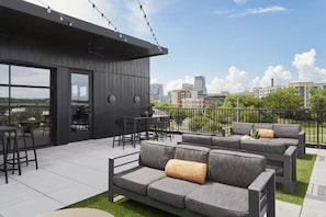 A rooftop terrace with outdoor seating, a dining area, and a city view. - Nashville Oasis at The Muse: Modern 2BR With Balcony & Rooftop Views (Nashville)