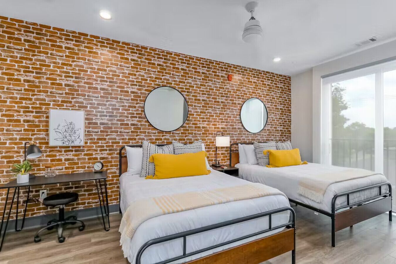 Una habitación de hotel moderna con dos camas, un escritorio y un ventanal grande.