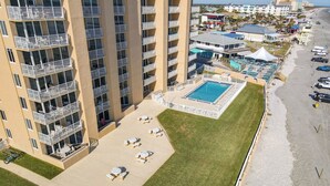 A high-rise hotel with a swimming pool, outdoor seating, and a beach view. - Oceania Beach Club 606 (New Smyrna Beach)