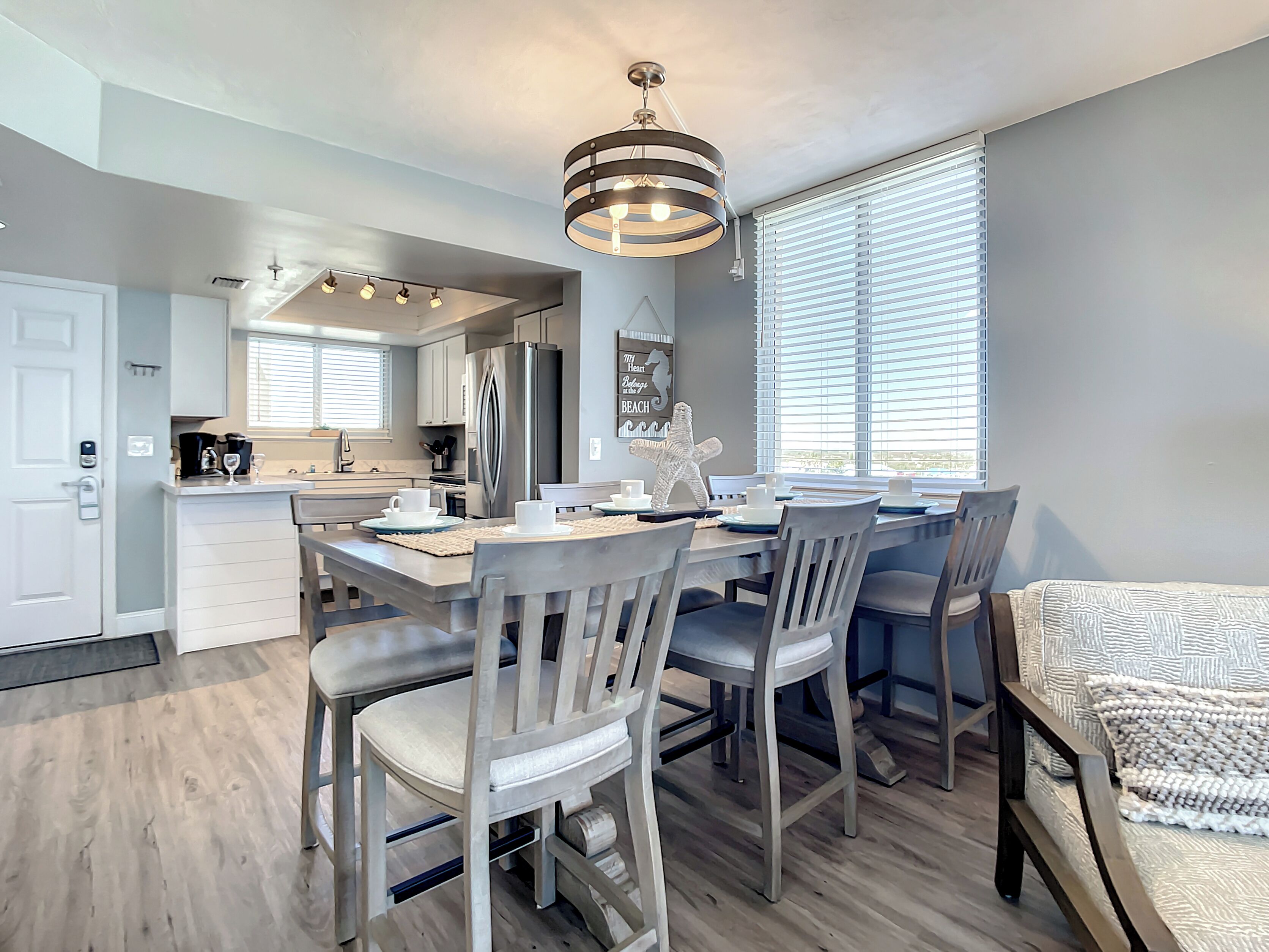 A modern kitchen with a dining area, featuring a large island, stainless steel appliances, and a pendant light.