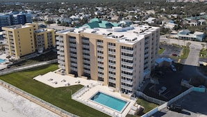 A multi-story hotel with a rooftop pool and a parking area. - Oceania Beach Club 207 (New Smyrna Beach)