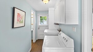 A laundry room with white cabinets, a washing machine, and a dryer. - Neighborhood Retreat - Large Yard Family Fire Pit (Nashville)