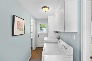 Une buanderie avec des armoires blanches, un lave-linge et un sèche-linge.
