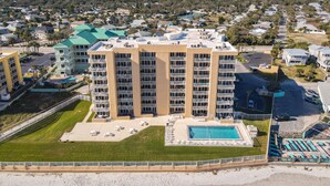 A high-rise hotel with multiple balconies, a swimming pool, and a beach view. - Oceania Beach Club 503 (New Smyrna Beach)