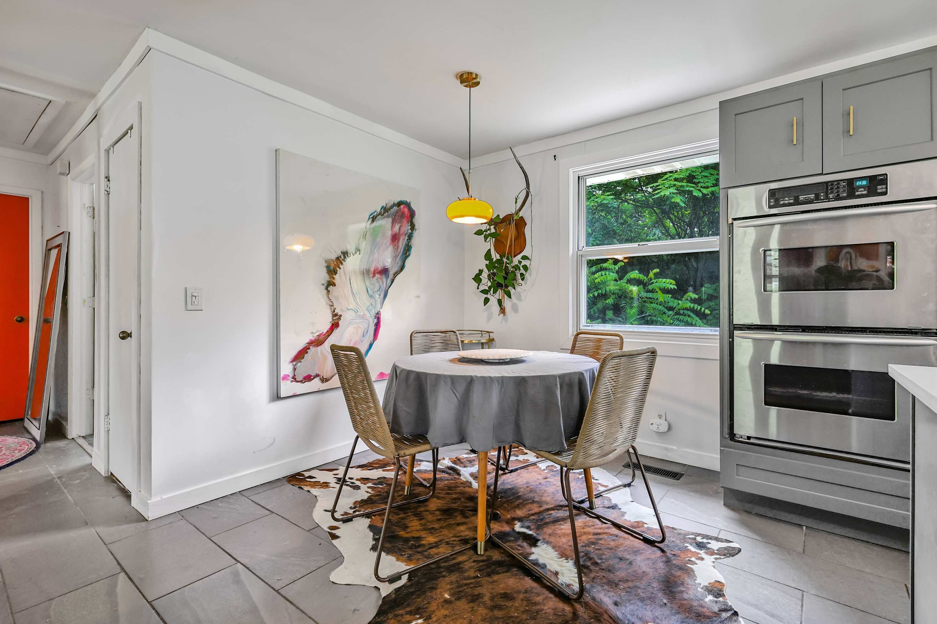 A modern kitchen with a round dining table, a large window, and a built-in oven.