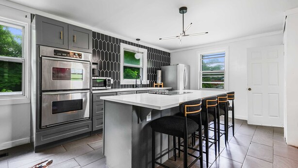 A modern kitchen with a central island, stainless steel appliances, and a bar area with stools. - Bachelorette Retreat in Nashville (Nashville)