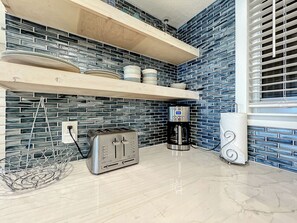 A kitchen with a toaster, coffee maker, and shelves with dishes. - Oceania Beach Club 305 (New Smyrna Beach)