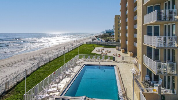 Un hotel con piscina, vistas a la playa y varios balcones.