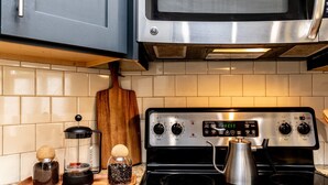 A kitchen with a stainless steel stove, a microwave above it, and a wooden cutting board on the counter. - Cashville Near Music Row Private Balcony (Nashville)