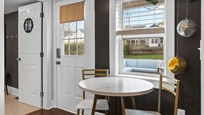 A room with a round table and chairs, a window with a view of a house, and a door with a sign. - Space Cowboy - Firepit, Huge Yard, Close2downtown (Nashville)