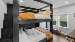 A bunk bed room with a staircase, a window with blinds, and a small seating area. - Space Cowboy - Firepit, Huge Yard, Close2downtown (Nashville)
