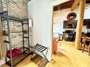 A room with a brick wall, a metal shelf unit, a red towel, and a wooden floor. - Willie (Nashville)