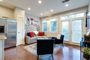 A modern kitchen with a stainless steel refrigerator, a dining area with a sofa and chairs, and a mural of Nashville on the wall. - I Love Nashville Near Music Row Free Parking (Nashville)
