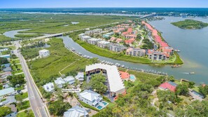 An aerial view of a coastal resort with a marina, walkways to the boat dock, and a mix of residential and commercial buildings. - Lala at the Beach 512 (New Smyrna Beach)