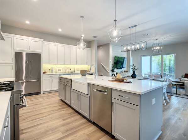 A modern kitchen with stainless steel appliances, white cabinetry, and a large island. - Lala at the Beach 512 (New Smyrna Beach)