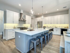 A modern kitchen with a large island, stainless steel appliances, and bar stools.