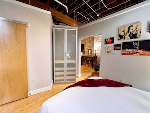Una camera da letto con un letto, una porta scorrevole, un'area pranzo con bancone e un muro in mattoni.