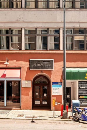 A building with a sign reading "Ambrose" above the entrance, a visible storefront with a sign saying "OPEN," and a motorcycle parked outside. - Waylon (Nashville)