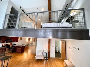 Un moderno loft con cucina, zona pranzo e un balcone con ringhiera in metallo.