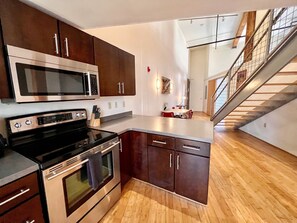 A modern kitchen with stainless steel appliances, wooden cabinets, and a herringbone-patterned floor. - Elvis (Nashville)