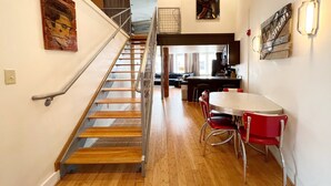 Eine Treppe führt zu einer oberen Ebene, ein Essbereich mit roten Stühlen und Kunstwerke an den Wänden.