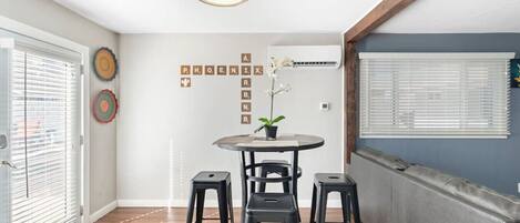 A modern kitchen with a round table, two stools, and a potted orchid.