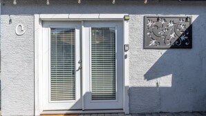 A white door with two glass panels and a decorative metal sign on the wall. - Central Phoenix Casita Unit C (Phoenix)