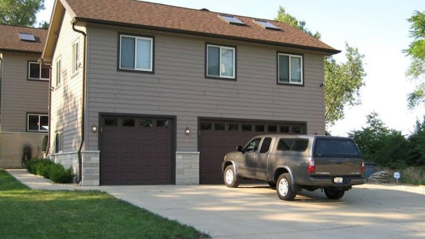 A two-story house with a garage and a parked SUV. - Coach House at Elyon Hall (Gary)
