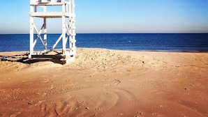 A beach with a white lifeguard tower. - Coach House at Elyon Hall (Gary)