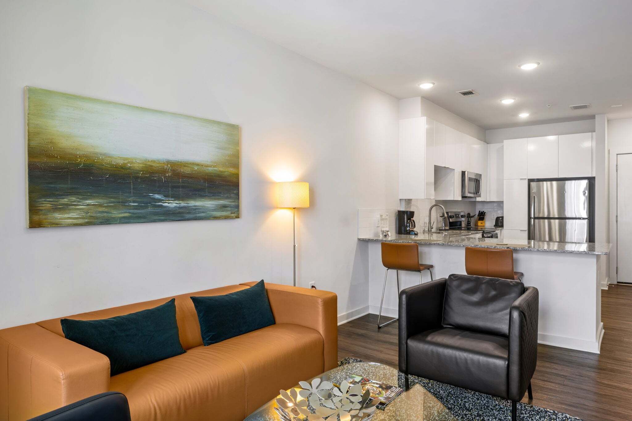 Un salon moderne avec un canapé, une table basse et un tableau accroché au mur.