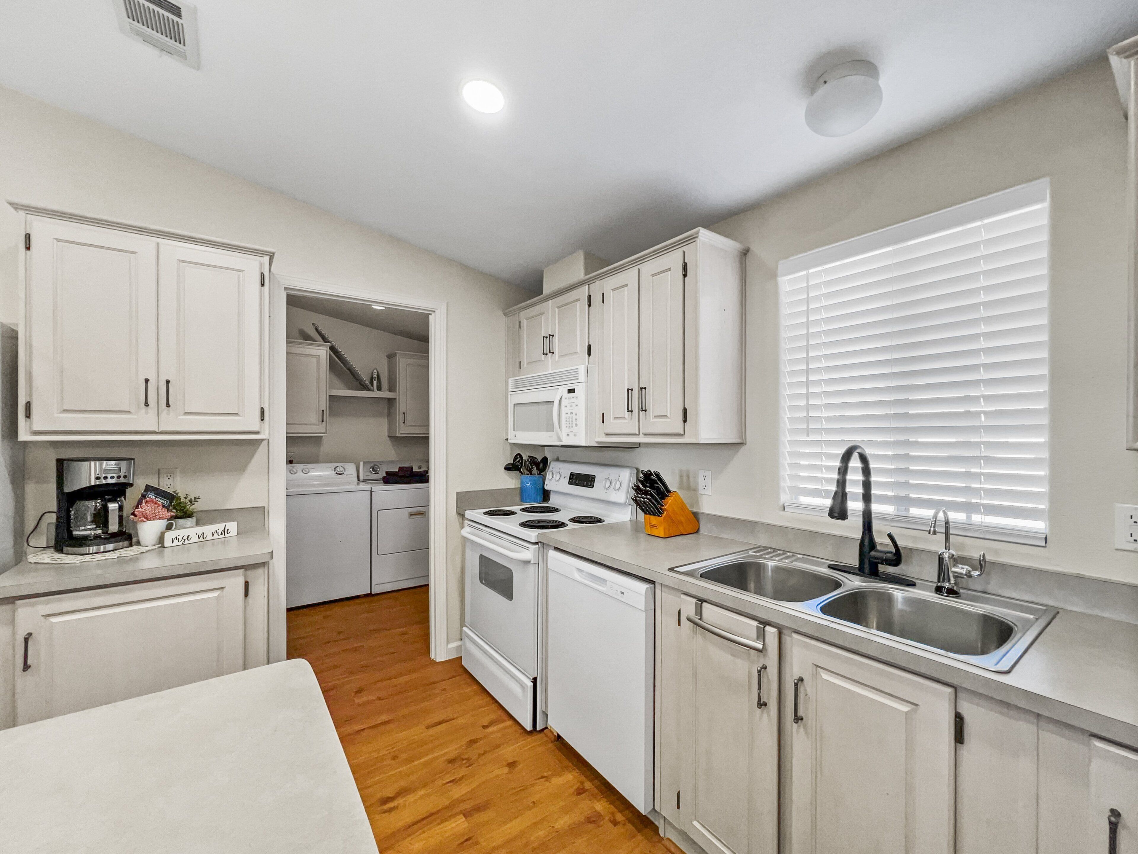 A compact kitchen with white cabinets, a microwave, a sink, and a dishwasher.
