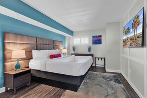 A modern bedroom with a large bed, a nightstand, a bedside table, and a window with blinds. - Oceanfront Penthouse! Heated Indoor Waterpark! Dunes Village Resort (Myrtle Beach)