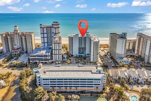 A coastal hotel complex with multiple high-rise buildings, a parking area, and a view of the ocean. - Oceanfront Penthouse! Heated Indoor Waterpark! Dunes Village Resort (Myrtle Beach)
