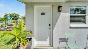 A white door with the number 8820, a small outdoor chair, and a potted plant. - 8820 Rocky Creek Drive Unit A (Tampa)