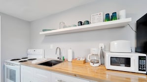A modern kitchen with white appliances, a wooden countertop, and a white backsplash. - 8820 Rocky Creek Drive Unit A (Tampa)
