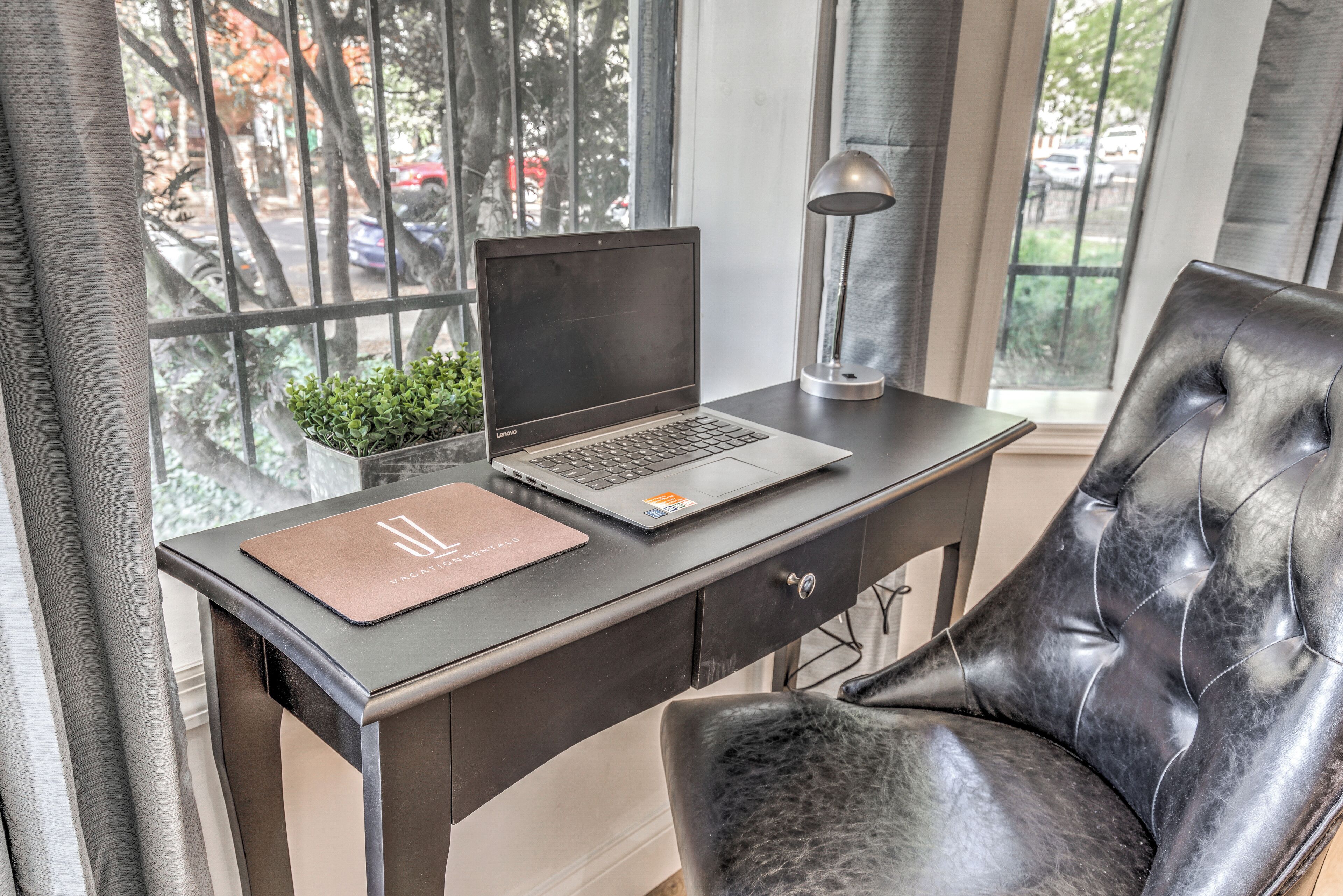A desk with a laptop, a lamp, and a leather chair.
