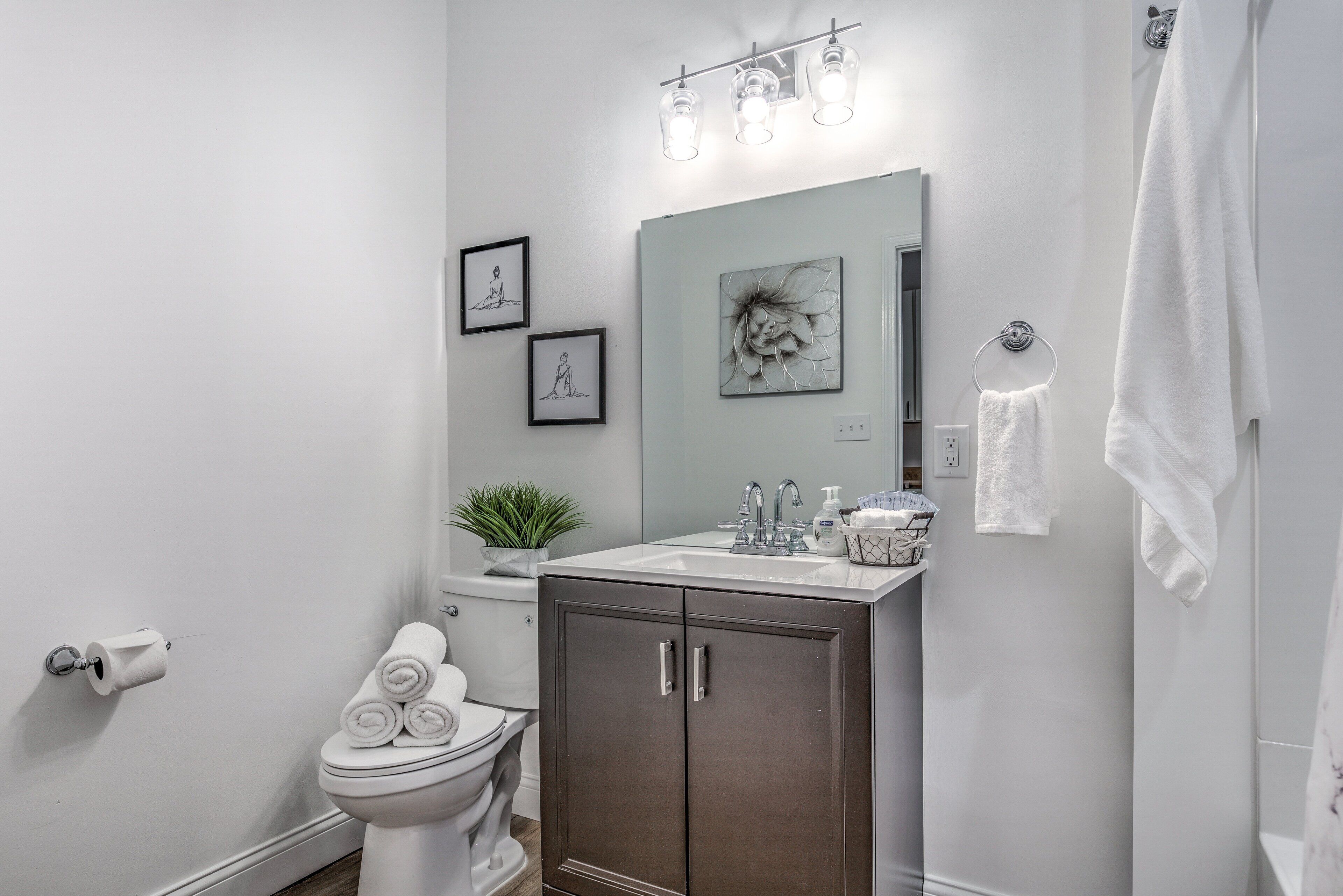 A modern bathroom with a toilet, sink, cabinet, and towel rack.