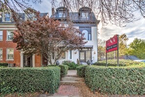 A two-story building with a brick facade, a large tree in front, and a sign indicating 'Puzzle McTwice.' - 4632 First Floor Hidden Gem (St. Louis)