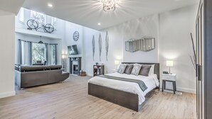 Ein modernes Schlafzimmer mit einem großen Bett, einer Couch und einem Kamin.