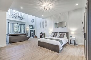 A modern bedroom with a large bed, a sofa, and a fireplace. - 4632 First Floor Hidden Gem (St. Louis)