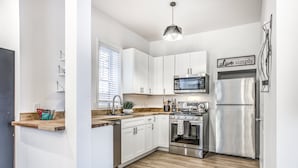 A modern kitchen with white cabinets, stainless steel appliances, a wooden countertop, and a 'Live simply' sign. - 4632 First Floor Hidden Gem (St. Louis)